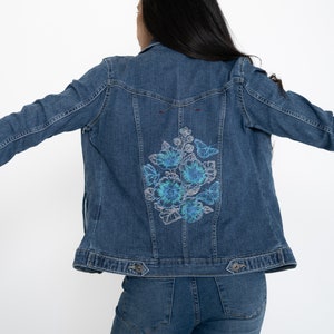 Denim Jacket for women with embroidered back, boho look. Design is a bouquet of blue flowers.