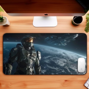 Puede incluir: Un tapete de ratón para juegos negro y verde con una escena espacial que presenta un soldado espacial verde y negro, una nave espacial y un planeta.