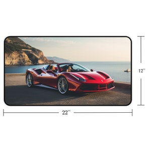 Pu&ograve; includere: Un'auto sportiva rossa decappottabile parcheggiata su una strada asfaltata con vista sull'oceano e una costa rocciosa sullo sfondo. L'auto &egrave; un tappetino per mouse di 22 pollici per 12 pollici.