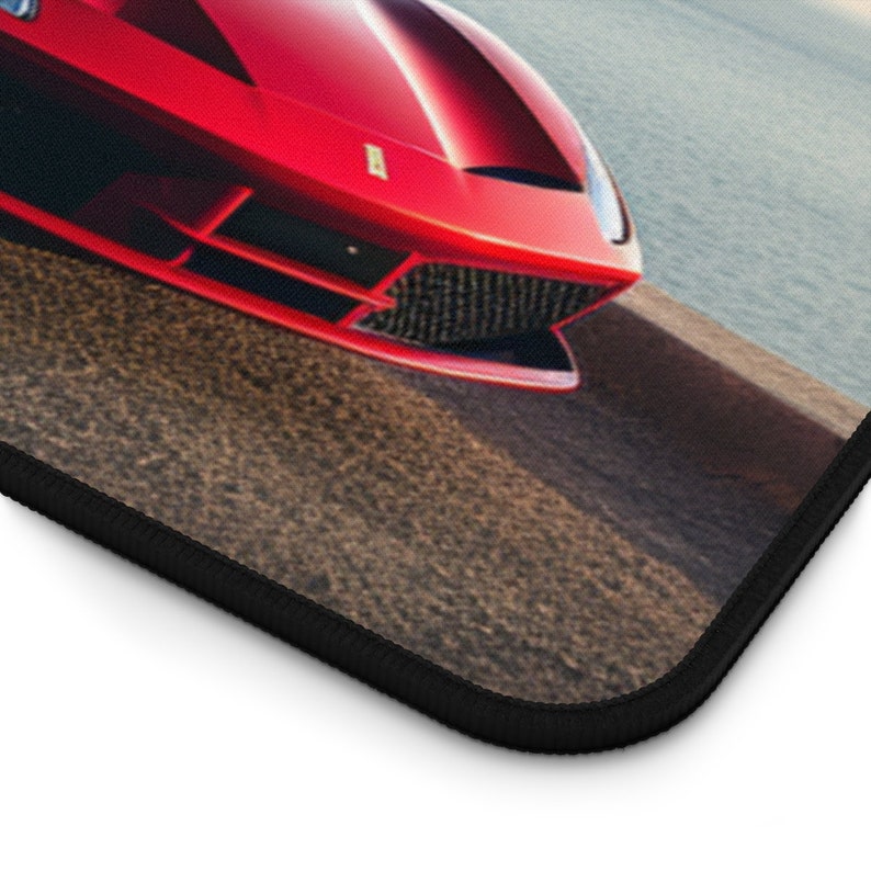Pu&ograve; includere: Un'auto sportiva Ferrari rossa parcheggiata su una strada asfaltata con vista sull'oceano sullo sfondo.