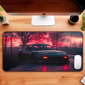 Könnte beinhalten: Schwarzes Mauspad mit Sportwagen-Illustration. Das dunkle Auto hat rote Scheinwerfer vor einem Sonnenuntergang. Eine weiße Maus und Tastatur liegen auf einem Holzschreibtisch.