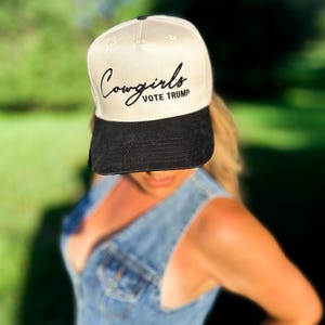 K&ouml;nnte beinhalten: Eine beige und schwarze Baseballkappe mit dem Text "Cowgirls VOTE TRUMP" in schwarzer Stickerei.