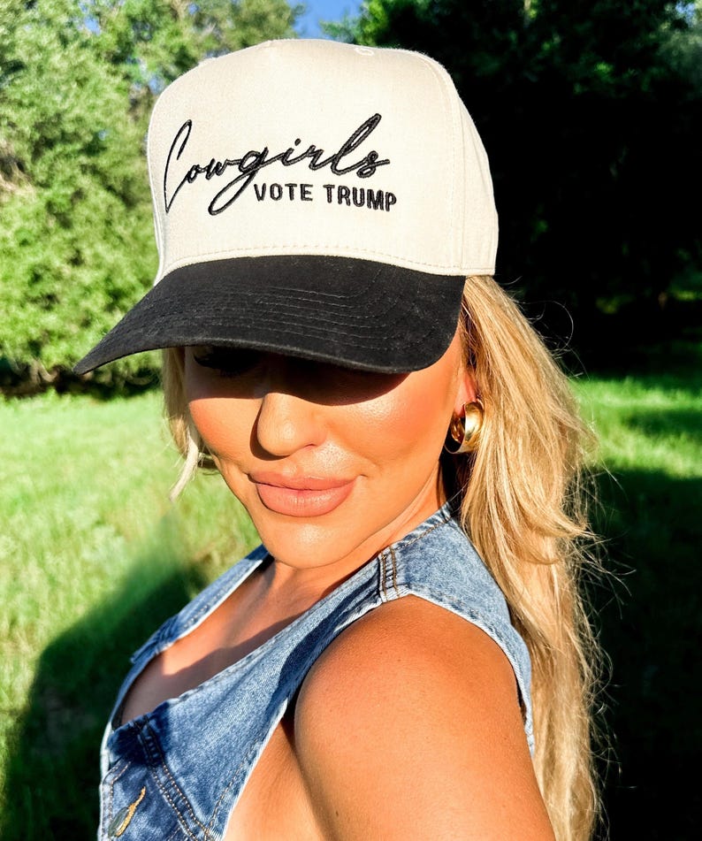 K&ouml;nnte beinhalten: Eine beige und schwarze Baseballkappe mit dem Text "Cowgirls Vote Trump" in schwarzer Stickerei.