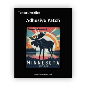 May include: An adhesive patch featuring a vintage-style illustration of a moose standing in front of a sunset with the text "Discover Adventure in... Minnesota Est. 1858" and the website "www.tokenatelier.com".