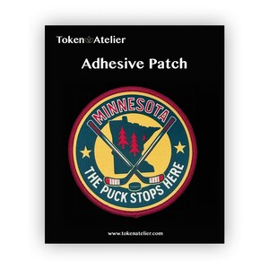 May include: Adhesive patch with a circular design featuring the word "Minnesota" and a state outline in yellow. The patch includes crossed hockey sticks, text that reads "The Puck Stops Here," and the Token Atelier logo.