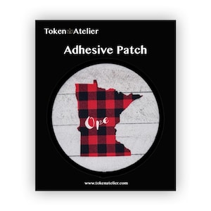 May include: A round, white, adhesive patch with a red and black plaid design of the state of Minnesota. The word "Ope" is written in white inside the state outline. The patch is on a black background with the text "Token Atelier" and "Adhesive Patch" above the patch and "www.tokenatelier.com" below the patch.