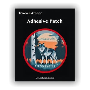 May include: Adhesive patch with a circular design featuring a wolf in a forest scene, with the text "MINNESOTA" and "L'Étoile du Nord". The patch is on a black background, with the words "Token Atelier" and "Adhesive Patch" at the top.