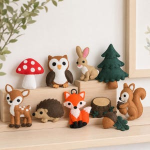 May include: A collection of felt woodland creatures and nature items including a red mushroom, brown owl, tan rabbit, green pine tree, brown deer, dark brown hedgehog, orange fox, tree stump, brown acorn, and a brown squirrel holding an acorn.