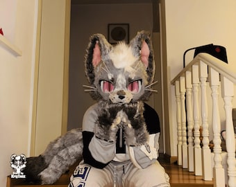 May include: A gray and white furry cat head with pink ears and red eyes, wearing a gray and black hoodie and gray sweatpants with a white logo. The cat is sitting on a wooden staircase with a white railing.