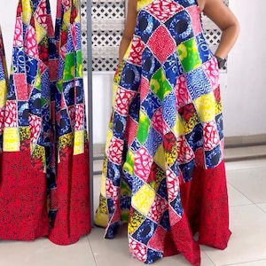 May include: A colorful maxi dress with a patchwork design featuring red, blue, green, yellow, and white squares. The dress has a sleeveless design and a square neckline.