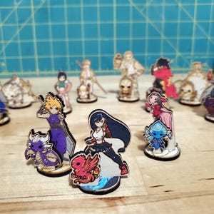 May include: A collection of wooden character figurines from a video game, featuring various characters in vibrant colors. The figurines are standing on small wooden bases, with detailed artwork and designs. The overall theme is fantasy and gaming.
