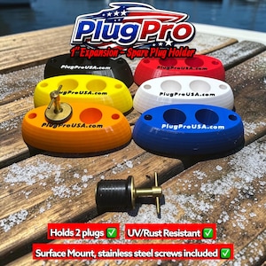 May include: A collection of oval 2.54 cm expansion spare plug holders in black, red, yellow, white, orange, and blue. Each holder features two circular openings, the text PlugProUSA.com, and a brass T-handle plug. The logo reads PlugPro 1-inch Expansion Spare Plug Holder.