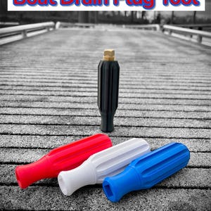 May include: A black boat drain plug tool with a gold cap stands upright, accompanied by three colorful handles: red, white, and blue. The text "Boat Drain Plug Tool" is displayed above. The tools are designed for boat maintenance.