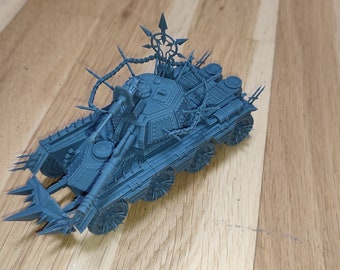 May include: A blue 3D printed model of a heavily armored, spiked, and chained war machine with a large cannon. The model is on a wooden surface.