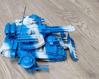 May include: A scale model tank featuring a blue and white camouflage paint scheme. The vehicle includes a main turret with a long barrel, secondary weapon systems, a front-mounted plow blade, and multiple articulated tracks on each side of the chassis.