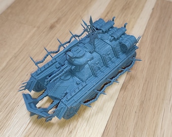 May include: A blue plastic model of a tank with a spiked fence around the top. The tank has a large cannon on top and several smaller cannons on the sides.