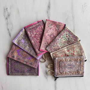 Könnte beinhalten: Ein Set aus neun bunten Stofftaschen mit Reißverschluss. Die Taschen sind fächerförmig angeordnet und haben verschiedene florale und geometrische Muster.
