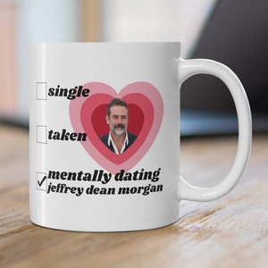 Könnte beinhalten: Weiße Keramik-Tasse mit herzförmigem Design in Rosa- und Rottönen, mit einem Foto von Jeffrey Dean Morgan. Der Text auf der Tasse lautet "Single", "Vergeben" und "Mental Dating Jeffrey Dean Morgan", mit einem Häkchen neben der letzten Option.