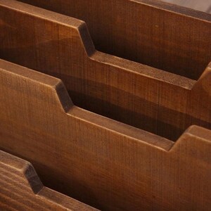Close-up view of three tier wooden compartments inside a vintage desk organiser with smooth carved edges