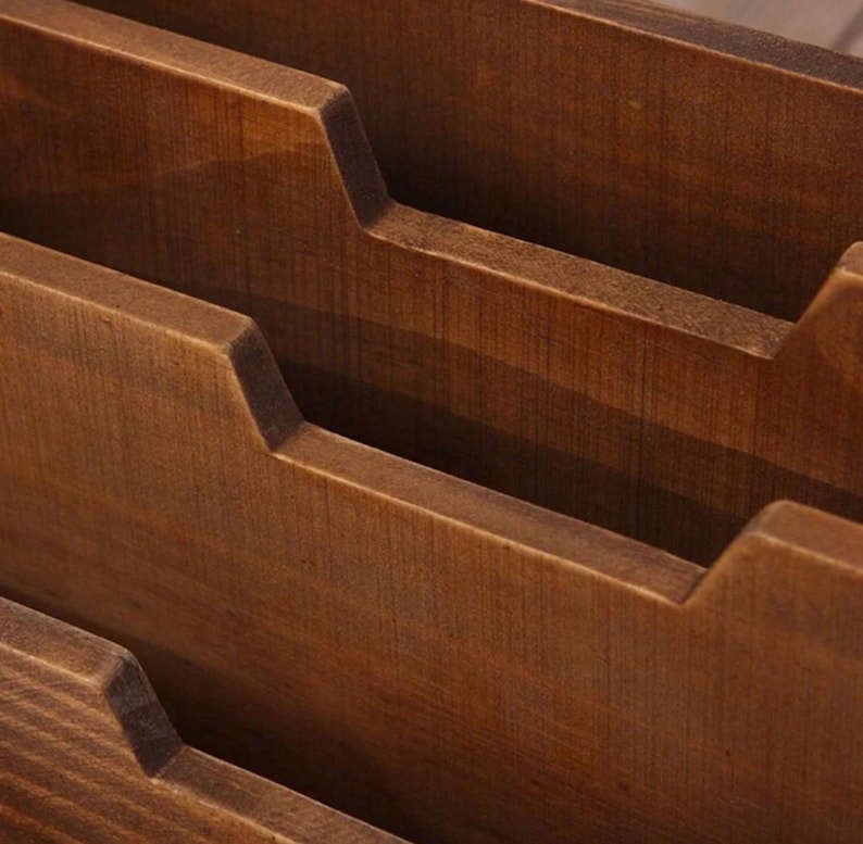 Close-up view of three tier wooden compartments inside a vintage desk organiser with smooth carved edges