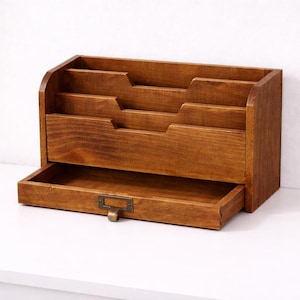 Vintage wooden desk organiser with three tier compartments and an open drawer on a white table against a white background