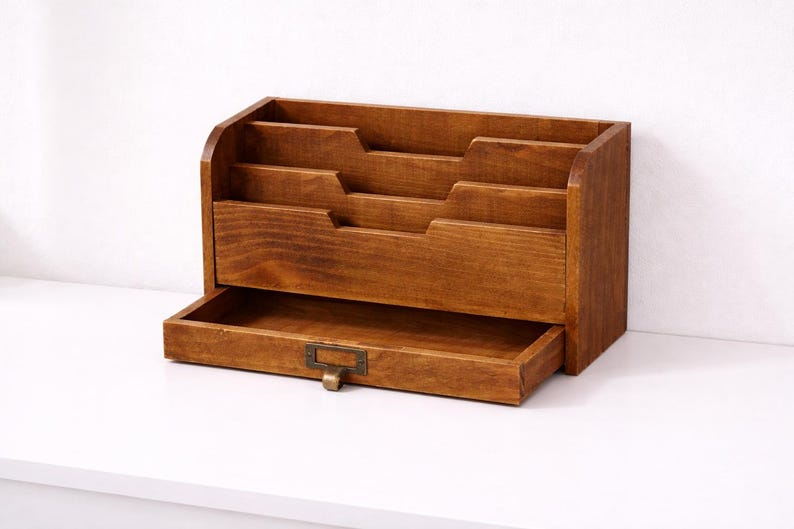 Vintage wooden desk organiser with three tier compartments and an open drawer on a white table against a white background