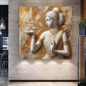 May include: A square wall art piece featuring a white and gold relief sculpture of a woman in traditional Indian attire. The artwork is set against a textured gold background, with intricate details in the jewelry and clothing.