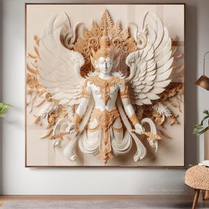Könnte beinhalten: Eine weiße und goldene Skulptur einer Gottheit mit Flügeln, in einem detaillierten, verzierten Stil geschnitzt. Die Skulptur ist vor einem cremefarbenen Hintergrund platziert.
