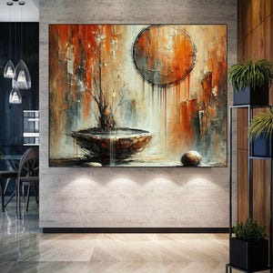 May include: Abstract painting with a large, round, orange and brown shape in the center, a smaller, round, gray stone in the bottom right corner, and a gray bowl with a brown interior in the bottom left corner. The painting is on a white wall in a modern home.