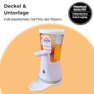 Könnte beinhalten: Ein weißer und klarer automatischer Seifenspender mit weißer Basis und einem transparenten Behälter mit orangefarbener Flüssigkeit. Der Spender hat einen weißen Auslauf und eine Ablage am Boden. Der Text auf dem Spender lautet "SAGROTAN HYGIENE SEIFE".