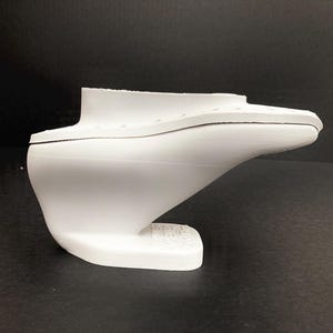 Könnte beinhalten: Weißes Plastikmodell eines Bootsrumpfes mit abgerundetem Boden und spitzem Bug. Das Modell ist dazu bestimmt, als Form für die Herstellung eines Bootes verwendet zu werden.