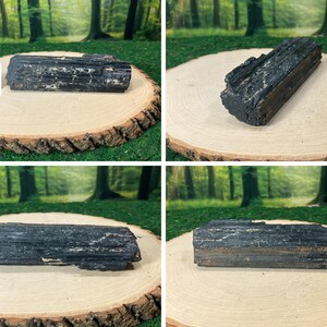 May include: Four images of raw black tourmaline crystals, each presented on a wooden slice. The crystals, with their rough texture, are set against a backdrop of green grass and trees. The crystals are a dark, almost black colour.