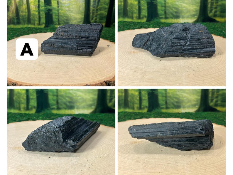 May include: Four raw, black tourmaline stones displayed on a light brown wooden surface. The stones have a rough, textured appearance and vary in shape and size. The background features a blurred forest scene.