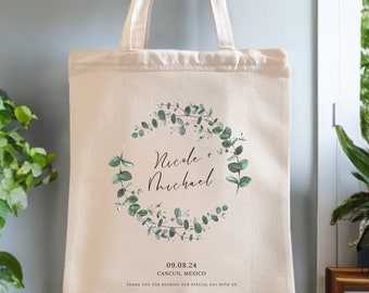 May include: A white canvas tote bag with a green eucalyptus wreath design. The bag has the names "Nicole + Michael" and the date "09.08.24" printed on it. The text "CANCUN, MEXICO" and "THANK YOU FOR SHARING OUR SPECIAL DAY WITH US" are also printed on the bag.