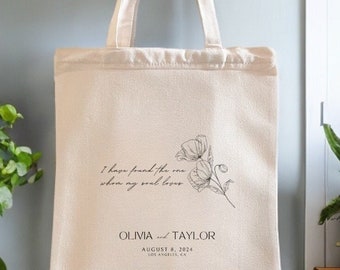 May include: A white canvas tote bag with black text and a floral design. The text reads "I have found the one when my soul loves" and "OLIVIA and TAYLOR AUGUST 8, 2024 LOS ANGELES, CA".