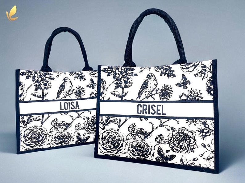 May include: Two black and white tote bags with floral and bird designs. The bags have black handles and a white stripe with the names 'Loisa' and 'Crisel' printed on them.