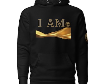 May include: Black hoodie with a gold design. The front features the words "I AM" in gold lettering above a gold flowing design. A gold emblem is on the right sleeve. The hoodie has a hood with drawstrings and a front pocket.