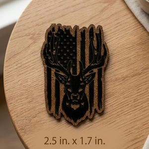 May include: A brown and black coaster featuring a deer head silhouette over an American flag design. The coaster measures 2.5 inches by 1.7 inches.