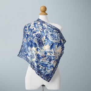 May include: A blue and white silk scarf with a floral pattern. The scarf is draped over a white mannequin.