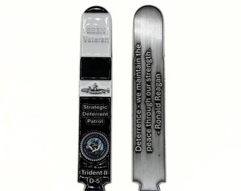 May include: A black and silver metal challenge coin with the words "SSBN Veteran" and "Strategic Deterrent Patrol" on one side. The other side has the words "Deterrence - we maintain the peace through our strength." - Ronald Reagan.
