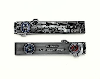 May include: A silver metal challenge coin with a detailed image of the USS Boxer aircraft carrier deck layout. The coin also features the ship's name, motto, and the US Navy and Marine Corps seals.
