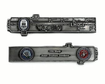 May include: A silver challenge coin with a detailed image of the USS Wasp (LHD-1) aircraft carrier. The coin features the seals of the Department of the Navy and the United States Marine Corps. The text "USS Wasp, Honor, Tradition, Excellence" is inscribed on the coin.