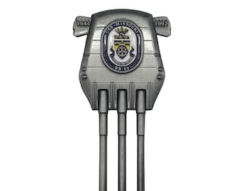 May include: A silver-toned metal pin shaped like a battleship gun turret with three barrels. The center features an oval emblem with the text USS MISSOURI, STRENGTH FOR FREEDOM, and BB-63. The years 1944 and 1992 are engraved on the upper left and right sides.