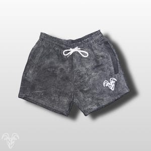 May include: Gray athletic shorts with a white goat logo and a drawstring waist.