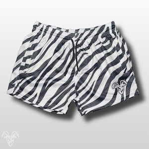 May include: White and black zebra print shorts with a drawstring waist. The shorts have a mesh-like texture and a small logo on the lower right side. The shorts are designed for athletic wear.