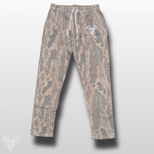 May include: Camouflage sweatpants with a white drawstring and a white logo of a ram's head on the left leg.