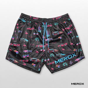 Könnte beinhalten: Schwarze Sportshorts mit einem sich wiederholenden Muster aus neonpinken und blauen Sportwagen, Palmen, Flamingos und Cocktails. Die Shorts haben einen hellblauen Kordelzug und das Wort MEROX in großen hellblauen Buchstaben auf dem Bein.