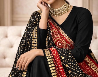May include: A black long-sleeved garment featuring a red panel with gold circular embellishments and a black shawl adorned with gold metallic accents. The ensemble is paired with a gold-toned necklace and matching drop earrings.