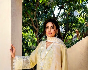 May include: A pale yellow long-sleeved tunic featuring intricate white floral embroidery, a V-neckline with a beaded tassel pendant, and wide lace cuffs. The garment is paired with a matching sheer, lightweight dupatta draped over the shoulders.