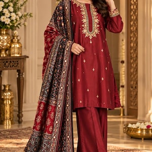May include: A deep maroon long-sleeved tunic with gold embroidery around the neckline and cuffs, paired with matching wide-leg trousers and a long, dark patterned shawl featuring intricate geometric designs and small reflective mirror accents.